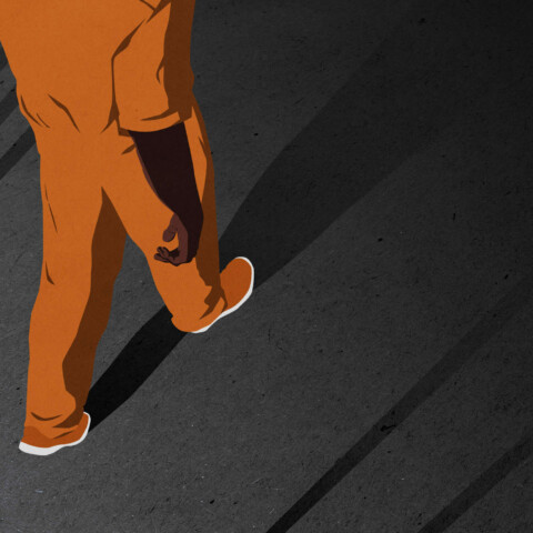 High angle looking down on a prisoner walking between the shadows of prison bars.