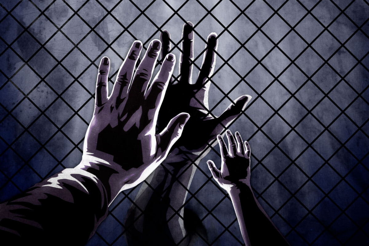 Hands connect through prison visitation window